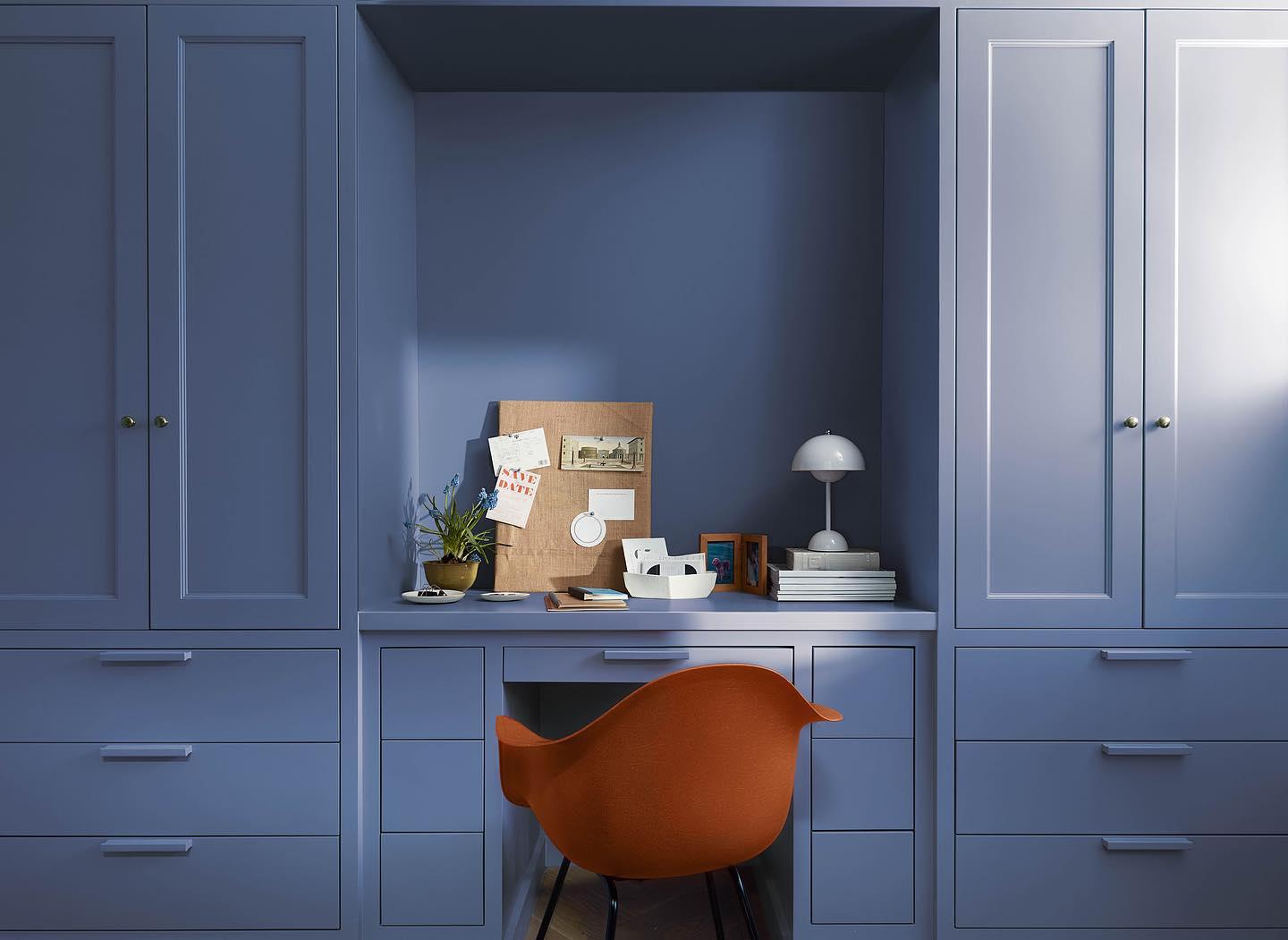 Benjamin Moore Blue Nova 2024 Color of the year painted on a blue built-in desk, paired with a dusty orange chair